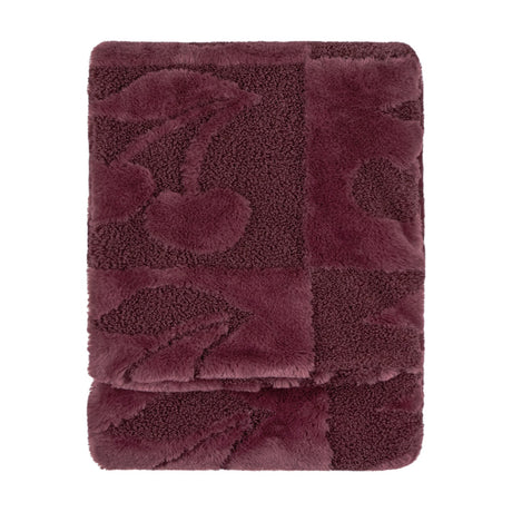 Folded faux fur throw in Morello purple with a checkerboard of smooth pile and boucle squares featuring a raised cherry design, shown on a plain white background.