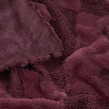 Close-up of the Fur Boucle Cherries Velvet Faux Fur Throw in Morello, showing textured boucle and smooth faux fur panels in a deep burgundy tone with folded edges.