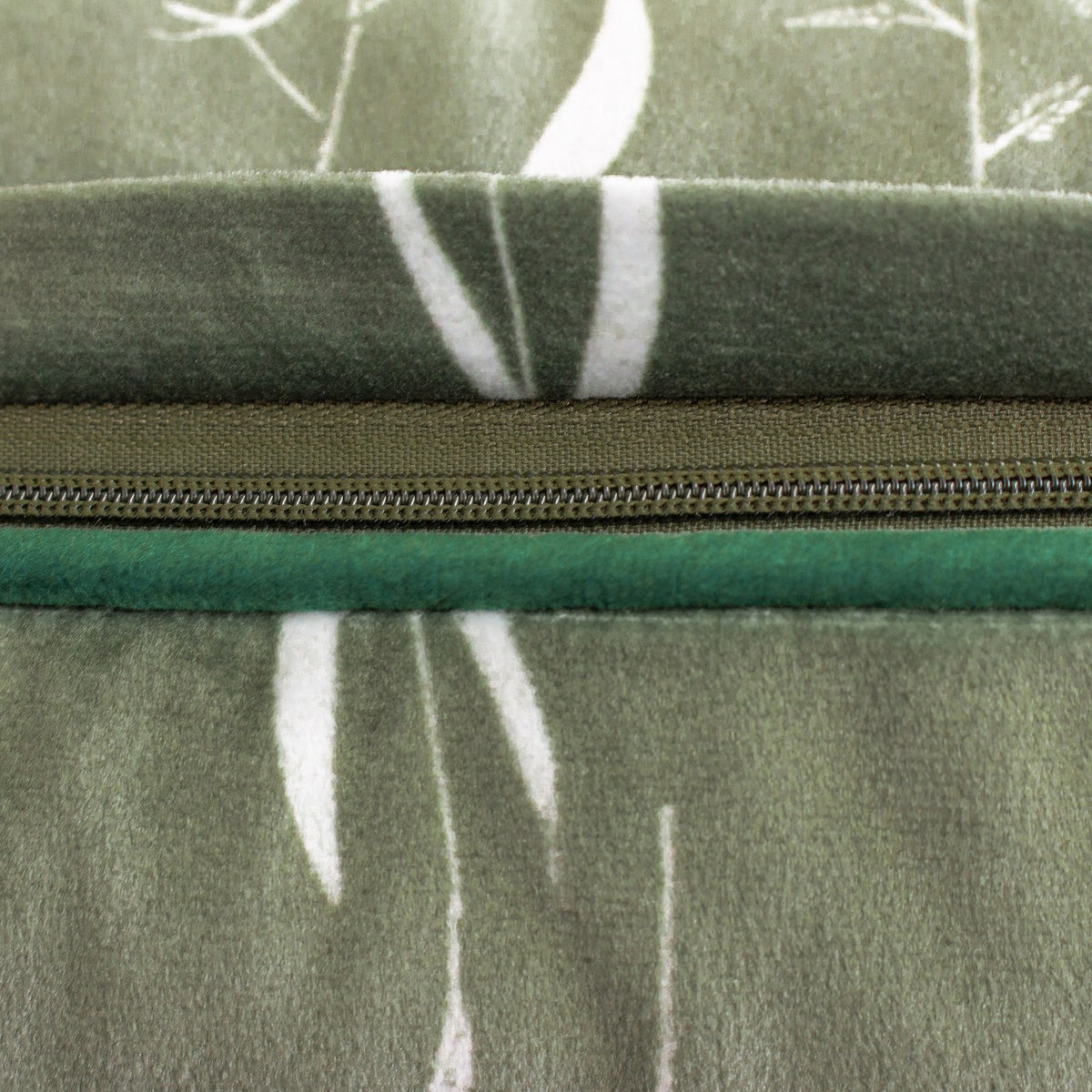 Close-up of the Fearne Reversible Velvet Cushion's zip closure, showing sage green botanical-print velvet on one side and plain emerald green velvet on the reverse.