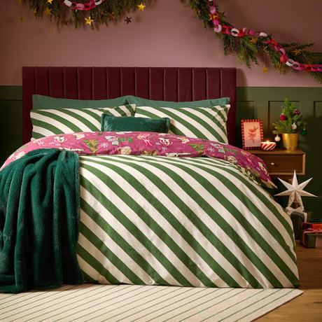 Reversible Feline Festive cotton duvet cover set with green and cream diagonal stripes, berry-red festive cat print trim, teal cushion and throw in a Christmas bedroom.