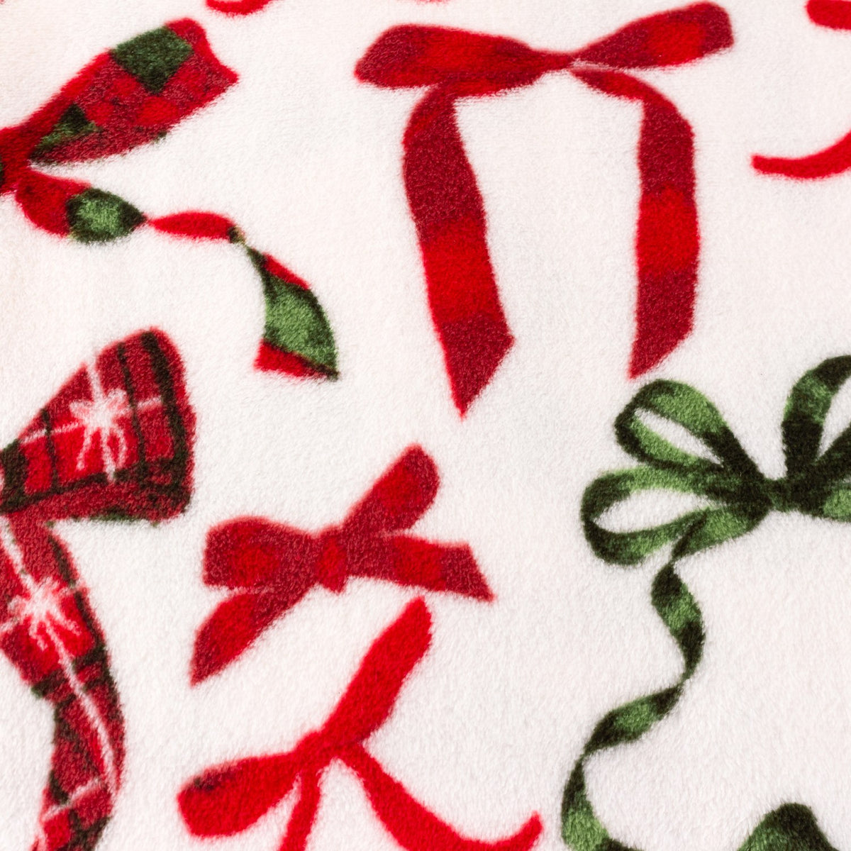 Nathaliefestivebows Bows Polyester Throw in Berry/Pine, a close-up of fleece fabric with red and pine green bow prints, some in tartan check, on a cream ground.