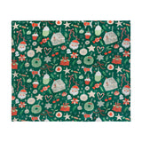 Emerald green polyester throw with a Christmas print of gingerbread houses, Santa faces, wreaths, dogs in jumpers, hot chocolate cups, and ribbon bows, shown flat.
