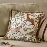 Fable Fox and Deer Woodland Cotton Cushion in Willow Green, square with dusky-pink fringe trim, shown on a sage sofa with cream and brown striped cushions.