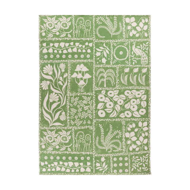 Forage Garden Floral Polyester Rug in sage green, patchwork grid of cream floral, fern, mushroom and peacock motifs on a flatweave base, shown on a plain white background.