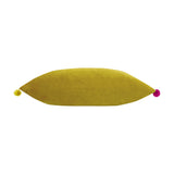 Fiesta Velvet Bamboo Cushion, a long rectangular bolster-style cushion in gold-green velvet with a yellow pompom on one end and a pink pompom on the other, shown on a plain white background.
