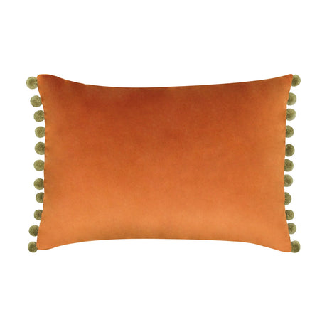 Fiesta Plain Velvet Cushion in rust orange, a rectangular lumbar-shaped cover with khaki-green pompom trim along both short edges, shown on a plain white background.