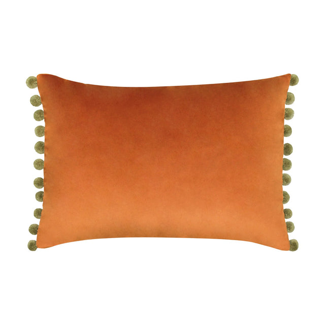 Fiesta Plain Velvet Cushion in rust orange, a rectangular lumbar-shaped cover with khaki-green pompom trim along both short edges, shown on a plain white background.