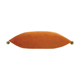 Fiesta Plain Velvet Cushion in rust orange, a rectangular lumbar-shaped cover with khaki-green pompoms at each end, shown on a plain white background.