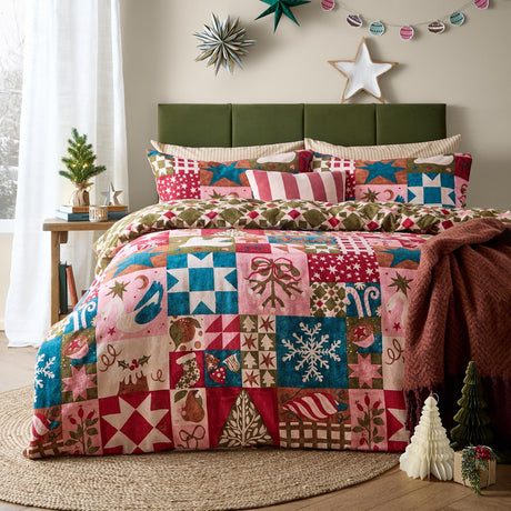 Fika Cotton Geometric Duvet Cover Set in Multi on a bed with matching pillowcases, styled in a bedroom with festive patchwork motifs of stars, snowflakes and swans in pink, teal, red and olive.