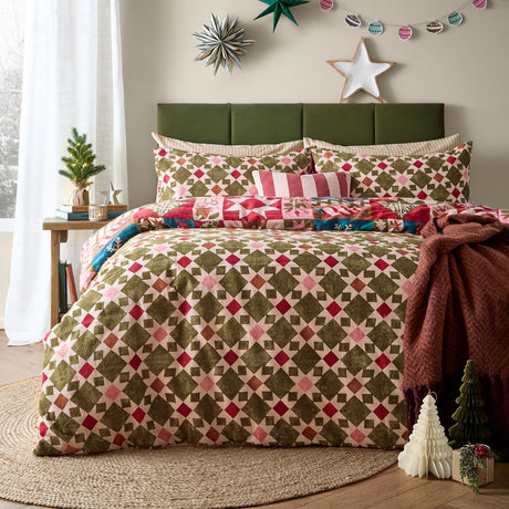 Fika Cotton Geometric Duvet Cover Set in Multi styled on a bed, showing the reversible diamond and star lattice print in olive, pink, red and cream with matching pillowcases in a bedroom setting.