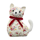 Cat-shaped door stop in floral print fabric with cream ears and tail, a red velvet bow at the neck, and stitched facial features, on a white background.