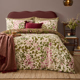 Flora Wilde Reversible Floral Duvet Cover Set in Chocolate, shown on a bed with cream pink and green wildflower print, burgundy velvet cushion, and dark red upholstered headboard.