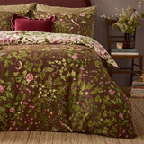 Flora Wilde Reversible Floral Duvet Cover Set in chocolate brown with pink and green wildflower print, styled on a bed with cream floral pillowcases in a bedroom setting.