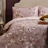 Floella Cotton Botanical Duvet Cover Set in dusky pink, styled on a bed with matching pillowcases showing a watercolour print of birds and trailing florals in cream and tan.