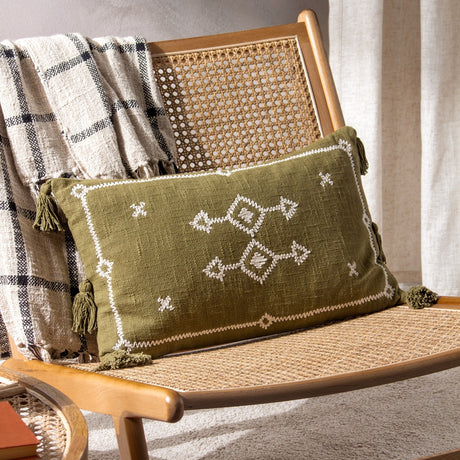 Folis Geometric Cotton Cushion in khaki with cream embroidered diamond motifs and corner tassels, styled on a rattan chair with a checked throw.