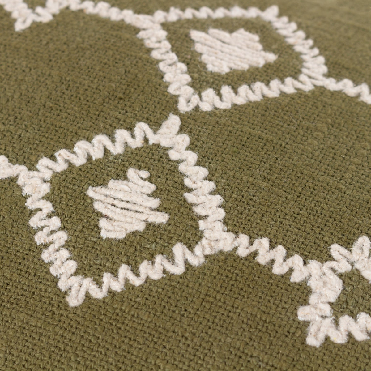 Close-up of the Folis Geometric Cotton Cushion in khaki, showing cream embroidered diamond motifs and zig-zag stitching on woven cotton fabric.