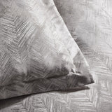 Folius Cotton Leaf Duvet Cover Set in silver, close-up of pillow and bedding showing a woven leaf jacquard pattern with a textured, shimmering finish.