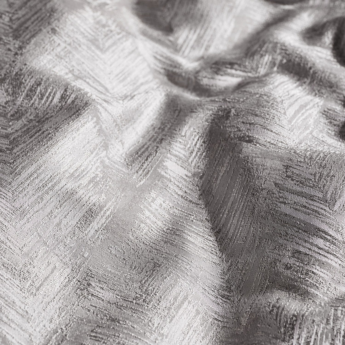 Close-up of the Folius Cotton Leaf Duvet Cover Set in silver, showing a jacquard woven leaf pattern with a raised, feathered texture on draped fabric.