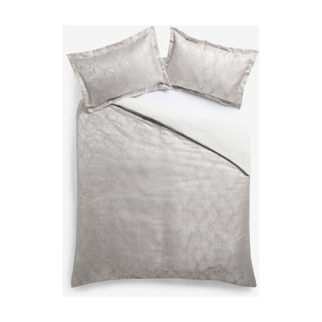 Folius Cotton Leaf Duvet Cover Set in silver on a bed, showing a jacquard woven leaf pattern with matching pillowcases against a plain white background.