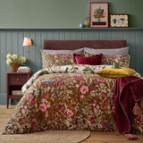 Forest Bloom reversible floral duvet cover set in chocolate brown with pink, blue and green wildflower print, styled with striped and burgundy cushions on a bedroom bed.