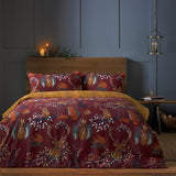 Forest Fauna Woodland Animal Duvet Cover Set in rust-red with stag, owl, fox and hare motifs, shown on a bed with a mustard reverse in a dark-panelled bedroom.