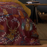 Forest Fauna Woodland Animal Duvet Cover Set in rust, shown on a bed with a mustard reverse, featuring stag, owl, fox and hare motifs in a bedroom setting.