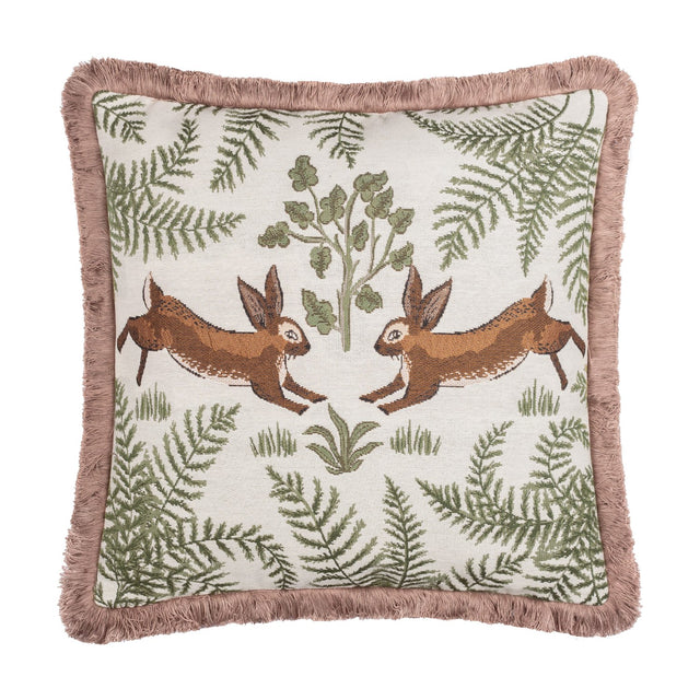 Fable Rabbits Woodland cotton cushion in willow green, square with pink fringe trim, featuring two mirrored leaping rabbits amid ferns and foliage on a cream ground, shown on a plain white background.