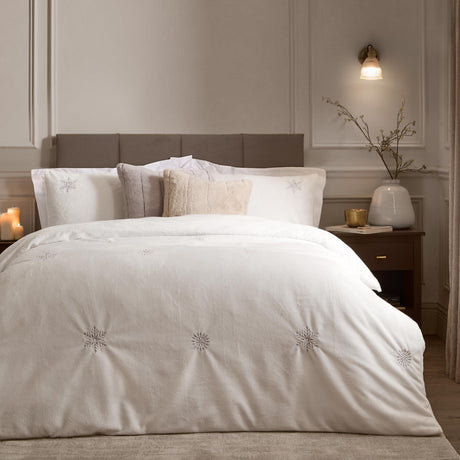 White Frosted Snowflake Polyester Embroidered Duvet Cover Set on a bed with matching pillowcases, embroidered silver-grey snowflakes, styled in a neutral-toned bedroom.