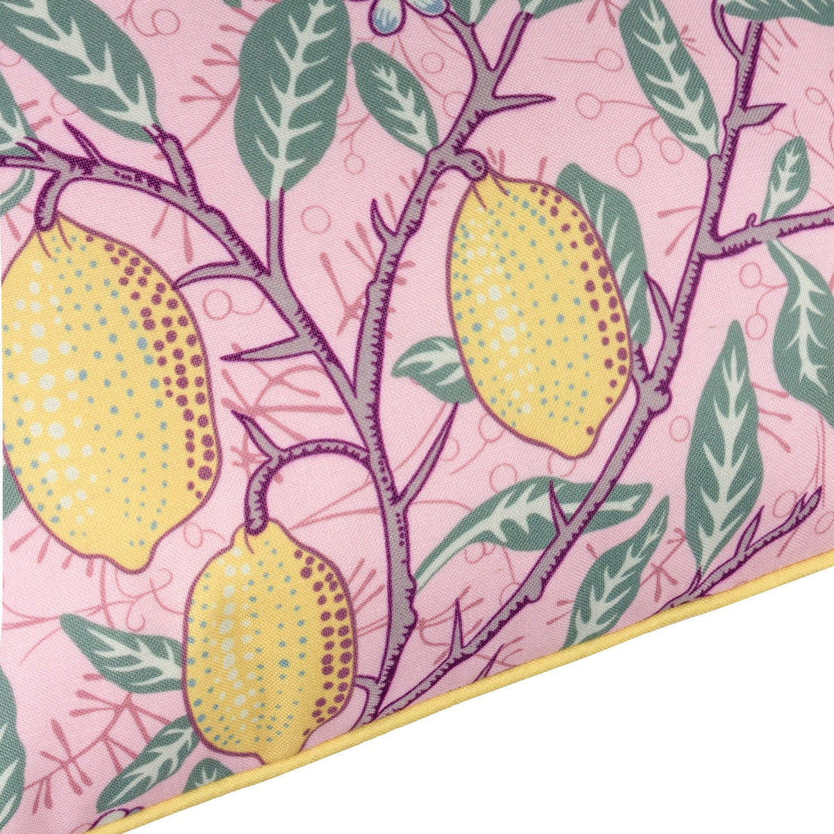 Close-up of the Fruits Piped Polyester Cushion in blush pink, showing lemons on thorned branches with green leaves and small floral motifs, edged with a yellow piped trim.