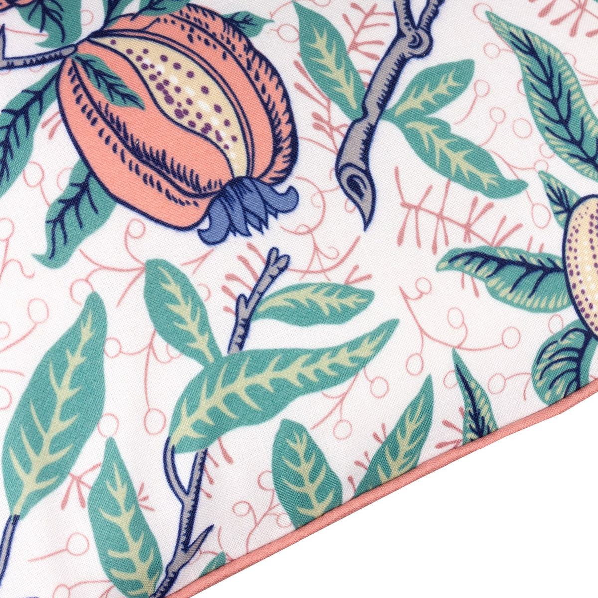 Fruits Piped Polyester Cushion in Coral/Lemon, close-up of pomegranate and citrus print with green leaves on pale ground, coral pink piped edge trim.