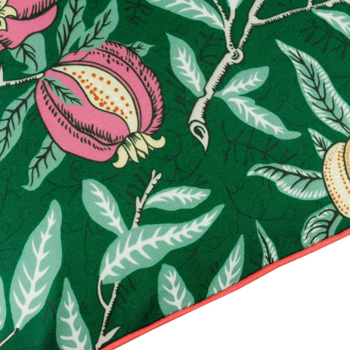 Close-up of the Fruits Piped Polyester Cushion in Forest Green, showing pink pomegranates, golden fruits and sage leaves on a green ground with a coral-orange piped edge trim.
