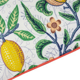 Close-up of Fruits Piped Polyester Cushion corner, showing lemons, pomegranate blooms and green leaves on a pale ground with tomato-red piped edge trim.
