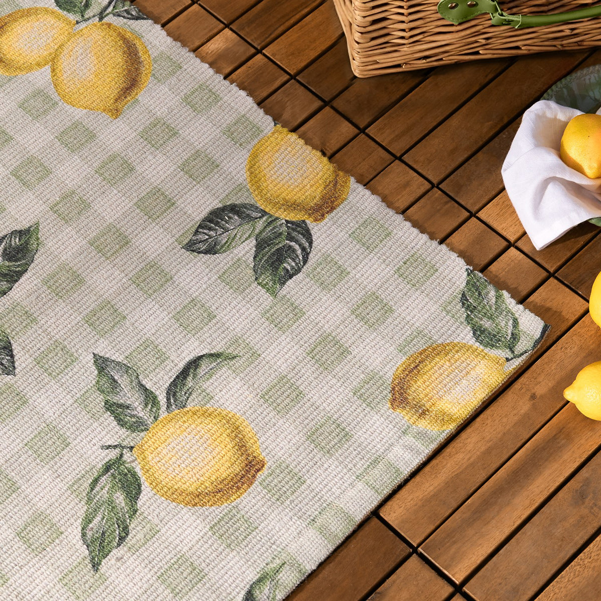Fruits Gingham Polyester Rug in Sage, showing a sage and cream check pattern with painted lemon and green leaf motifs, displayed on a wooden deck.