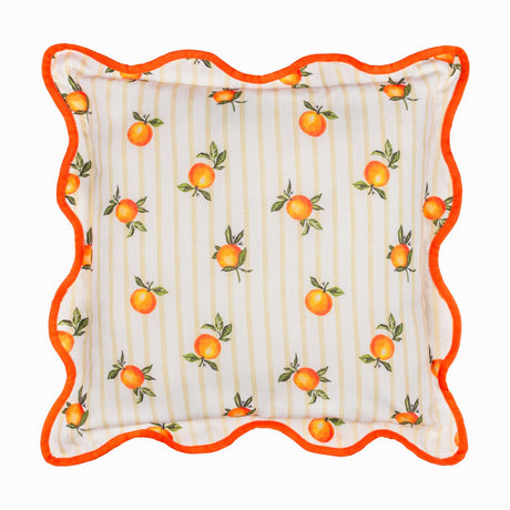 Square polyester cushion with a scattered orange print and green leaves on cream and yellow striped fabric, edged with a wavy orange piped border, shown on a white background.