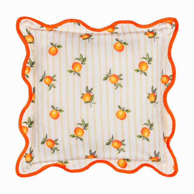 Square polyester cushion with a scattered orange print and green leaves on cream and yellow striped fabric, edged with a wavy orange piped border, shown on a white background.