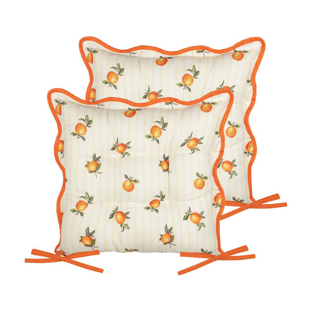 Two square tufted seat pads in yellow stripe fabric with scattered orange fruit print, edged in scalloped rust-orange piping and orange tie fastenings, shown on a white background.