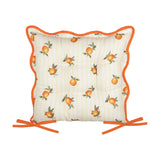 Square tufted seat pad in yellow stripe polyester with scattered orange fruit print, scalloped rust-orange piped edge, and two orange tie fastenings, shown on a white background.