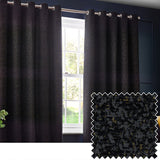 Galaxy Chenille Fully Lined Eyelet Curtains in black hang either side of a window on a metal pole, with a textured chenille fabric swatch showing gold flecks inset below.