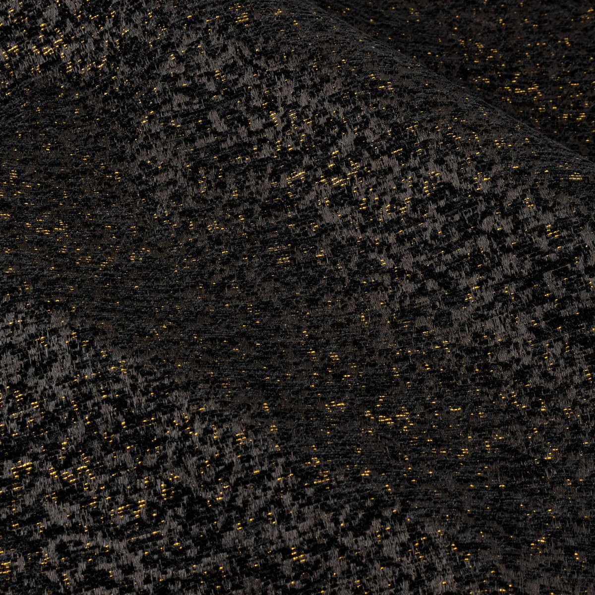 Close-up of Galaxy chenille eyelet curtain fabric in black, showing a soft textured weave flecked with gold metallic highlights.