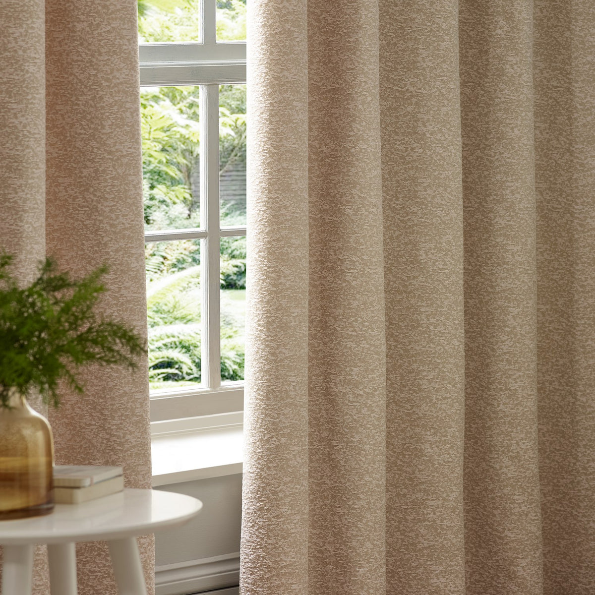 Galaxy Chenille Fully Lined Eyelet Curtains in Blush, showing textured chenille fabric with mottled pink and cream tones, hung beside a window in a living room setting.