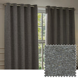 Galaxy Chenille fully lined eyelet curtains in charcoal, shown hanging on a metal pole beside a window in a living room, with a textured swatch inset showing flecked grey-black fabric.