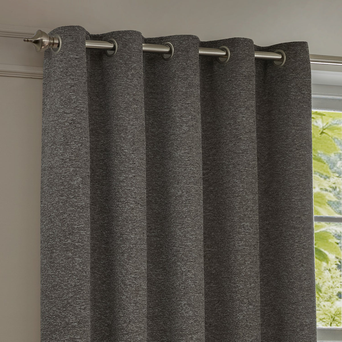 Galaxy Chenille fully lined eyelet curtain in charcoal, textured fabric with silver flecks, hung on a brushed metal pole beside a window.
