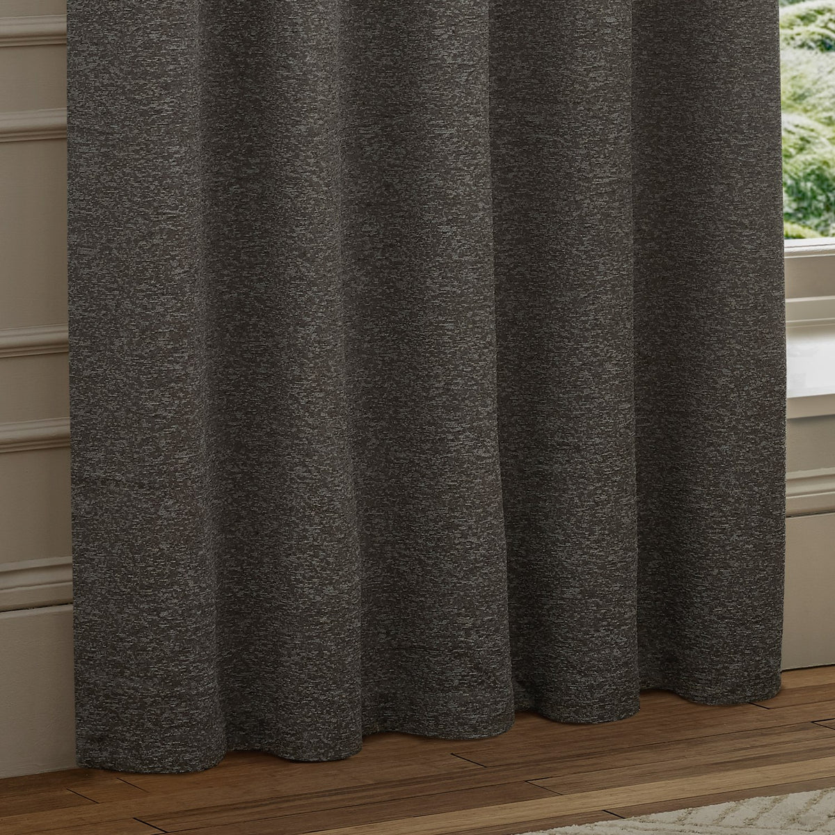 Galaxy Chenille Fully Lined Eyelet Curtains in charcoal, textured fabric with soft folds, hung by a window near a wood floor and painted wall panelling.
