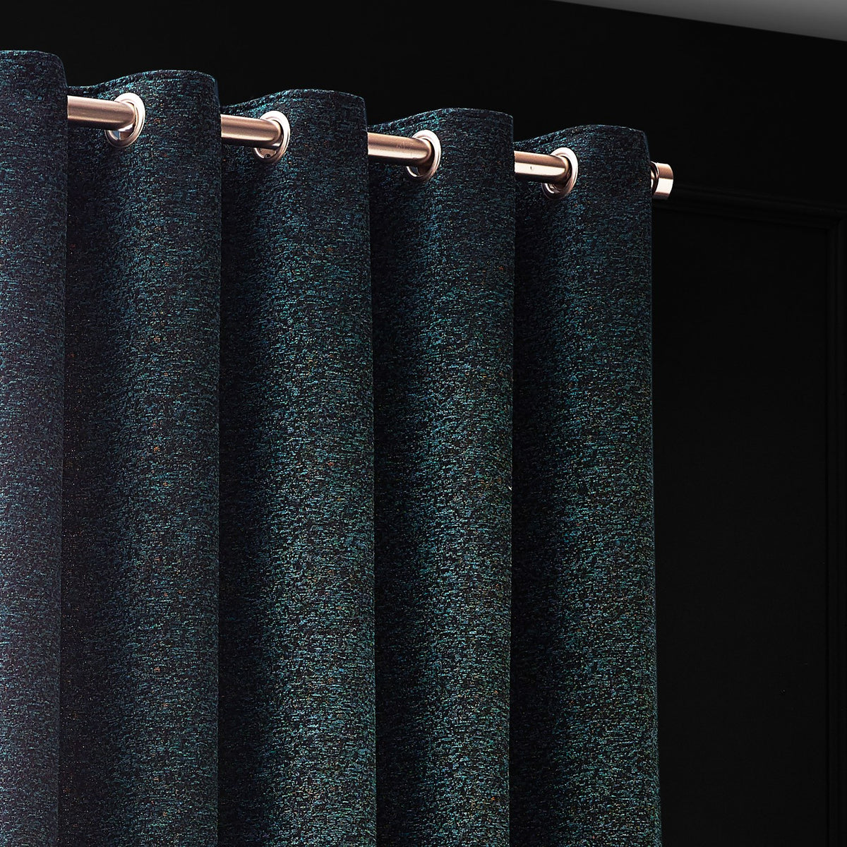 Galaxy Chenille Fully Lined Eyelet Curtains in emerald, close-up of textured fabric with golden flecks and eyelet headings on a copper-toned pole.