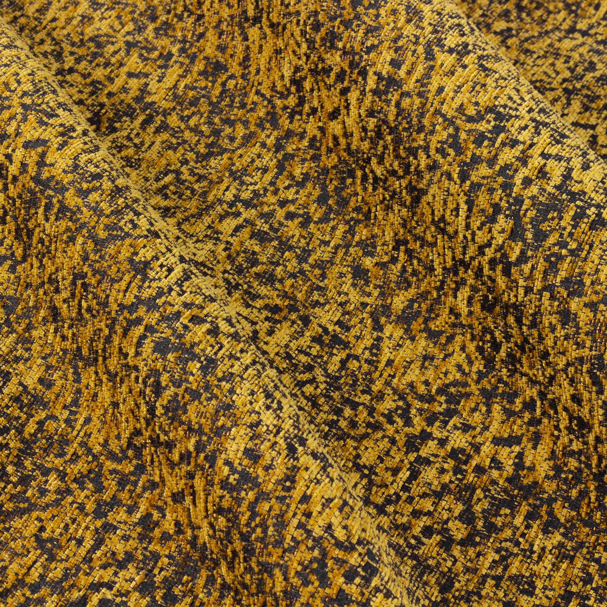 Close-up of Galaxy eyelet curtain fabric in gold, showing yarn-dyed chenille with a mottled, textured pattern over a dark base and soft folds.