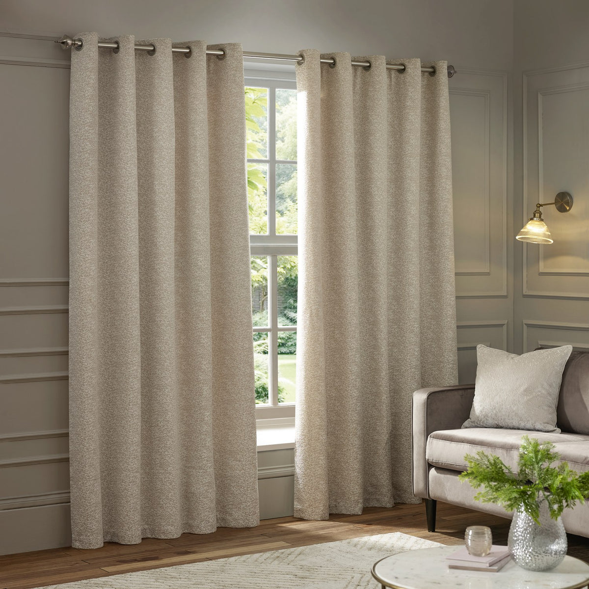 Galaxy Chenille Fully Lined Eyelet Curtains in ivory, shown hung on a metal pole in a living room beside a window, with a textured chenille finish and grommet header.