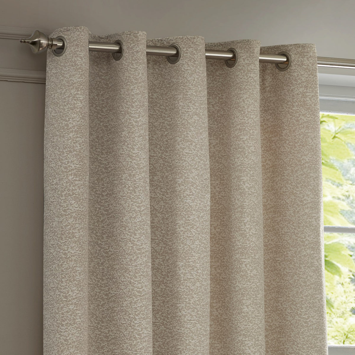 Galaxy Chenille Fully Lined Eyelet Curtains in ivory, textured woven fabric with silver eyelets on a brushed metal pole, shown against a window in a living room setting.