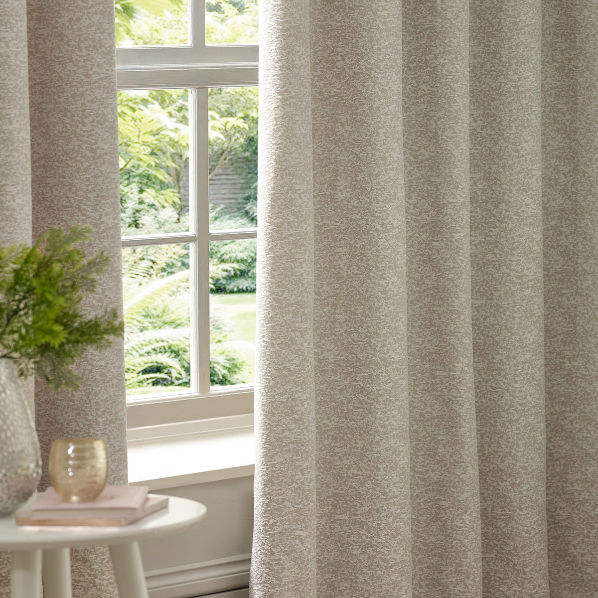 Galaxy Chenille Fully Lined Eyelet Curtains in ivory, textured chenille fabric with subtle flecked pattern, shown hanging by a window in a living room setting.