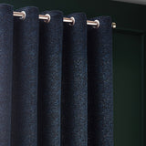 Galaxy Chenille Fully Lined Eyelet Curtains in navy, shown close-up on a brushed metal pole with eyelet rings, revealing a mottled chenille texture flecked with gold against a dark green wall.