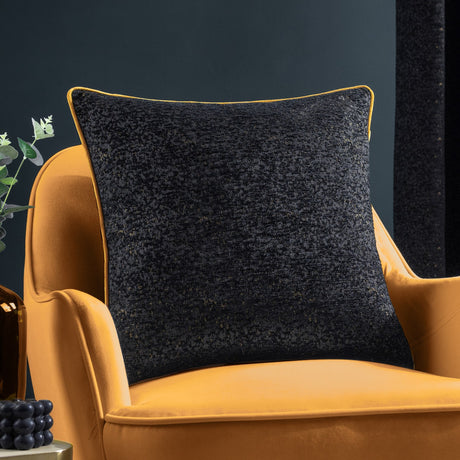 Galaxy Eyelet Chenille Cushion in black with gold-flecked textured pile and matching gold piping, shown on a mustard velvet armchair.